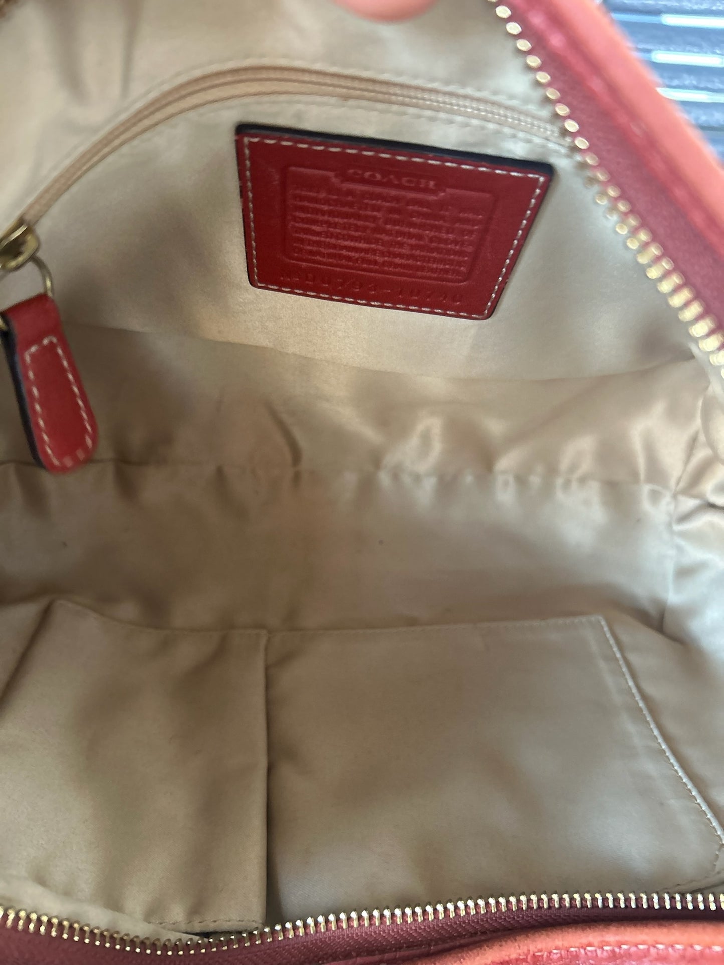 Inside view of a Coach hobo bag with pearl color liner showing pockets