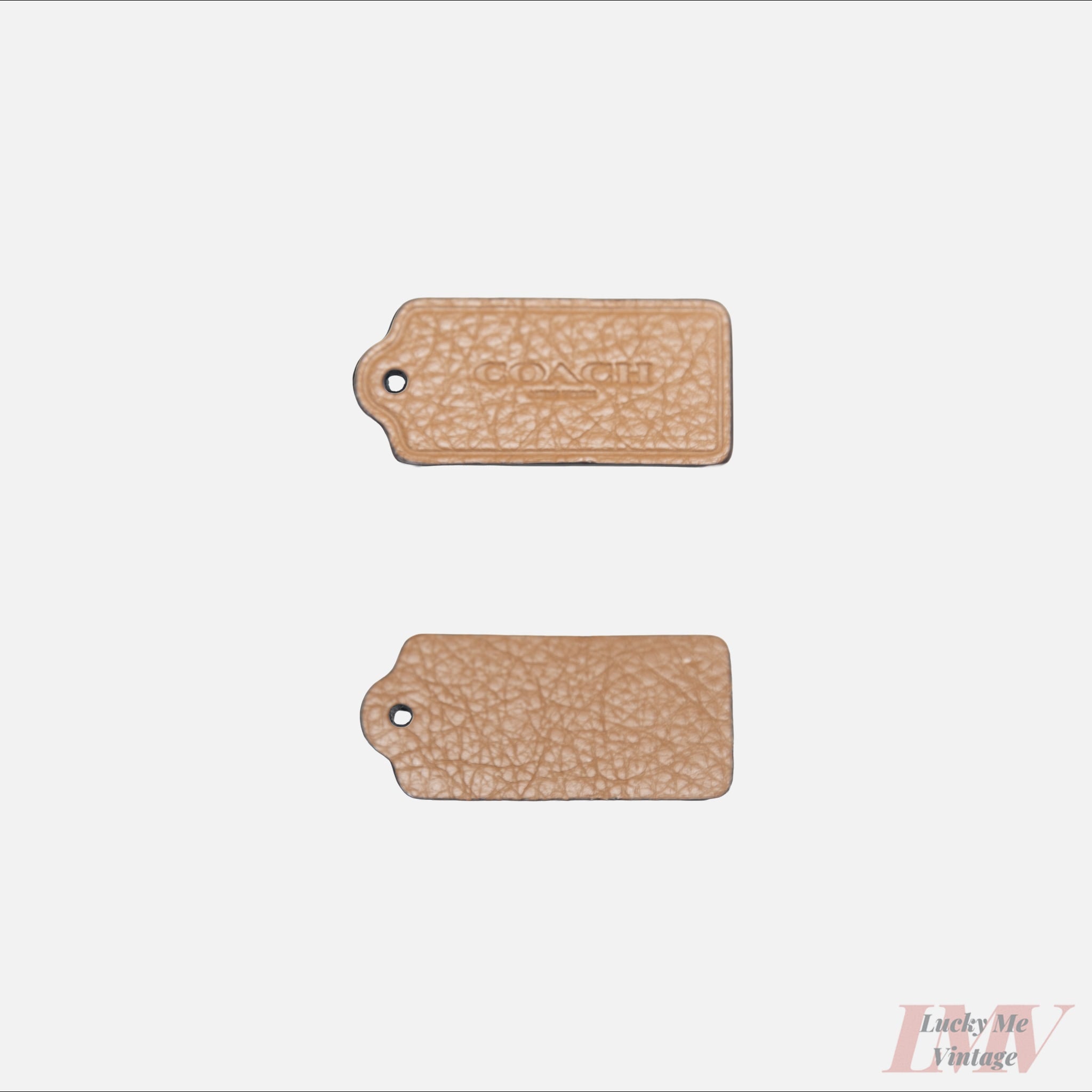 Two 2.5 inch peanut butter color leather tags showing front and back with 'Coach' branding on a white background. 
