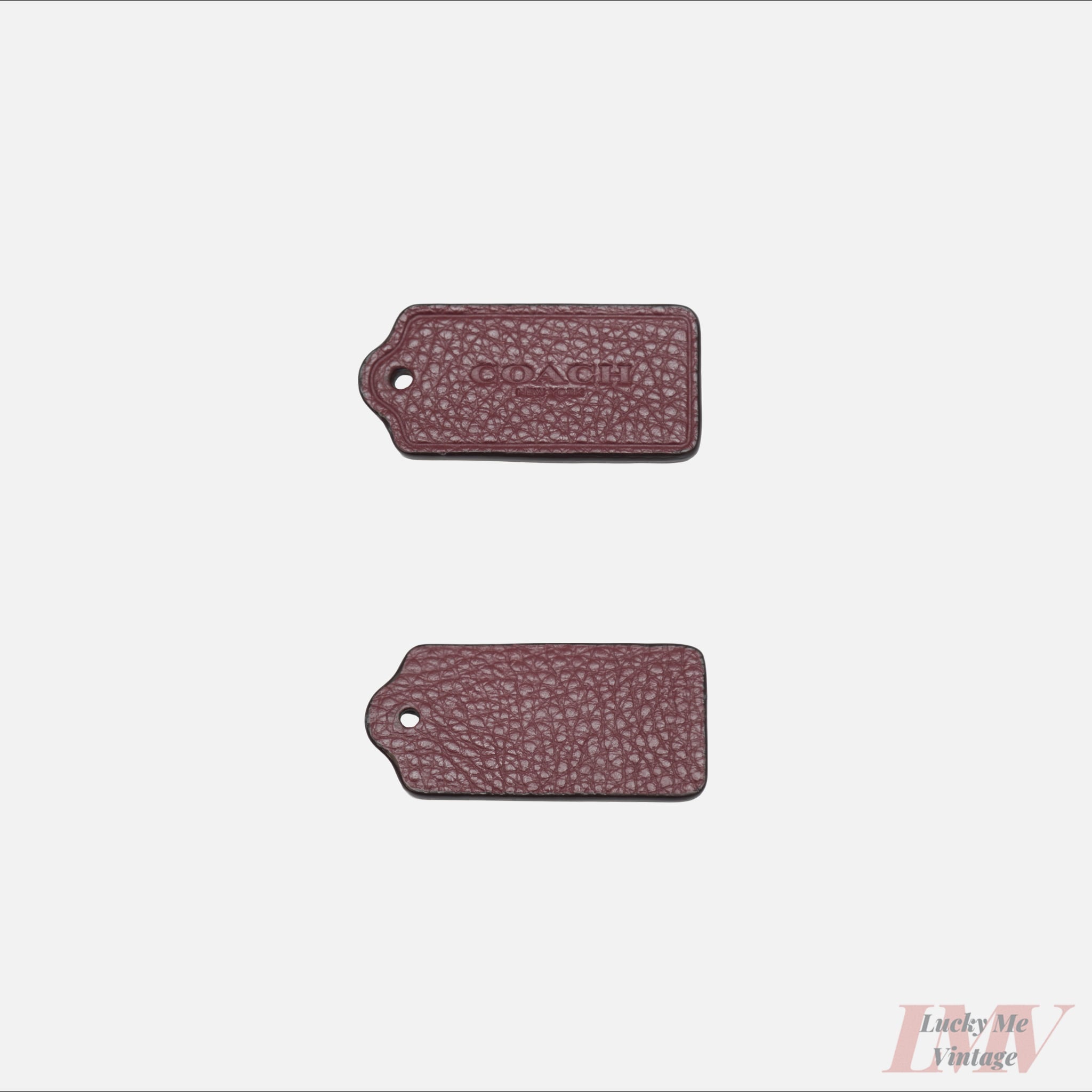 Two 2.5 inch rum raisin color leather tags showing front and back with 'Coach' branding on a white background. 